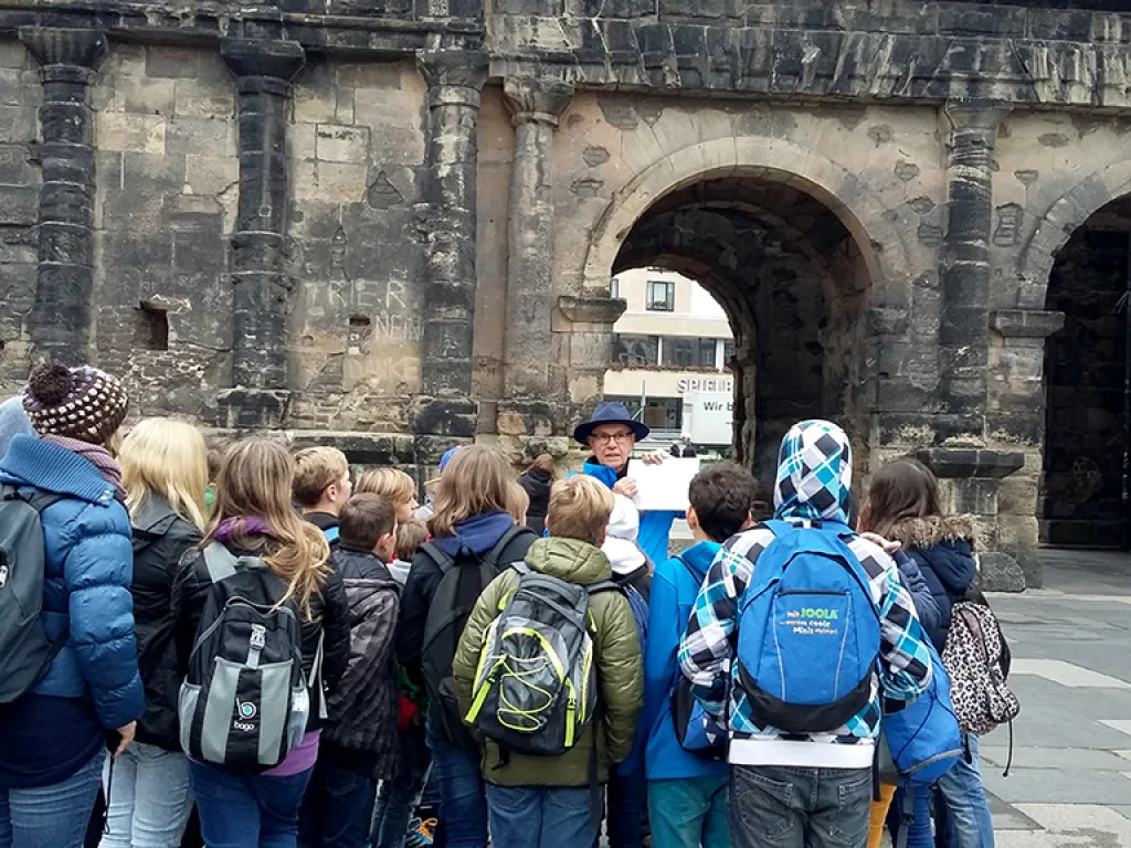 Jugendliche stehen mit Rucksäcken vor der Porta Nigra.